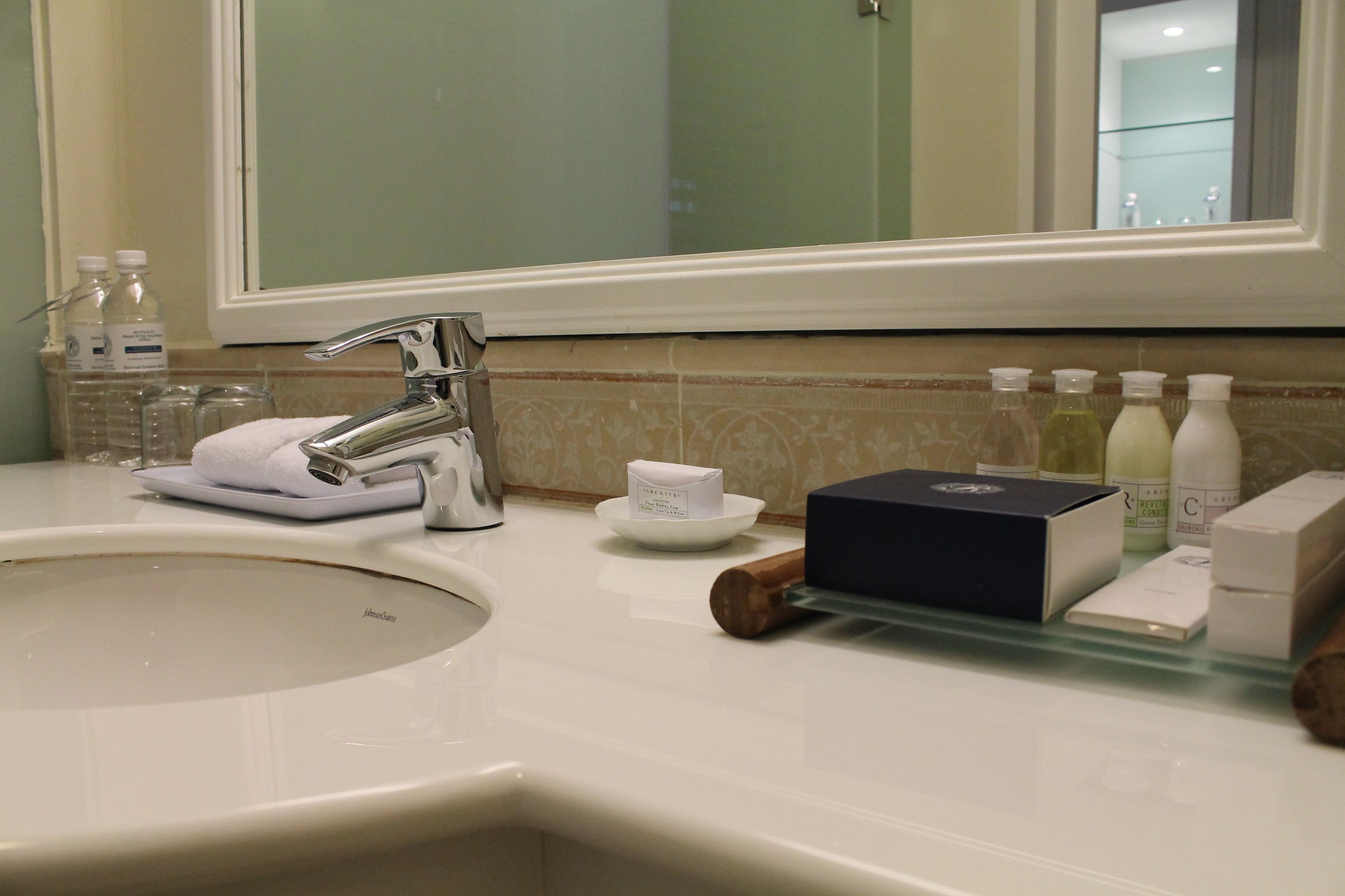 Un lavabo dans la salle de bain, avec un miroir au-dessus, une serviette et divers produits de toilette posés sur le comptoir.