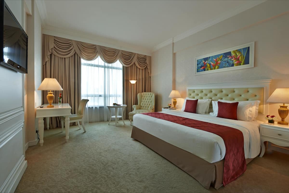 A hotel room with a large bed, two bedside tables, a TV, a desk, and a chair.