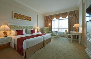 A hotel room with two beds, a sitting area with a chair and table, and a large window with curtains. - Royale Chulan Damansara (Petaling Jaya)
