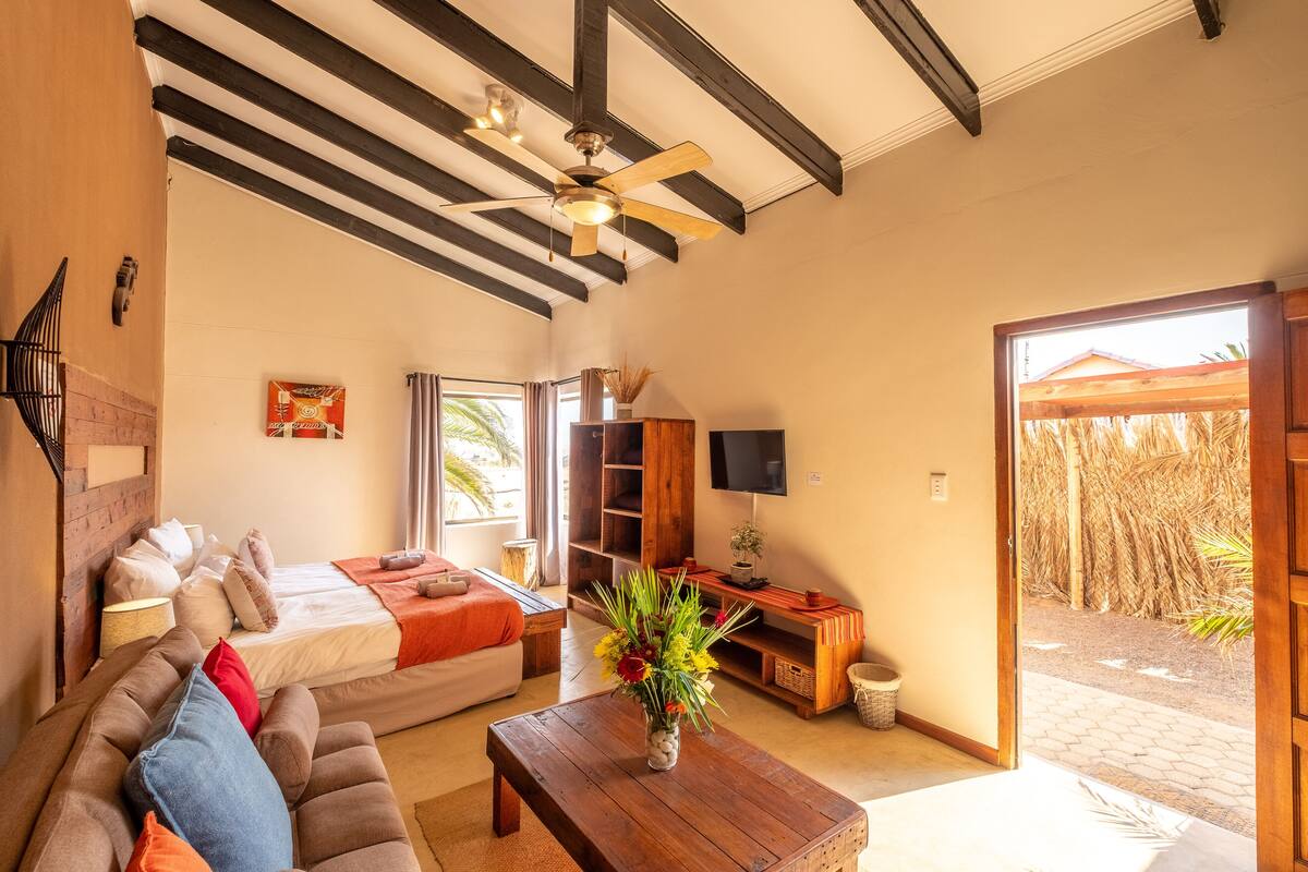 A spacious living area with a sofa, coffee table, and a bed with a TV.
