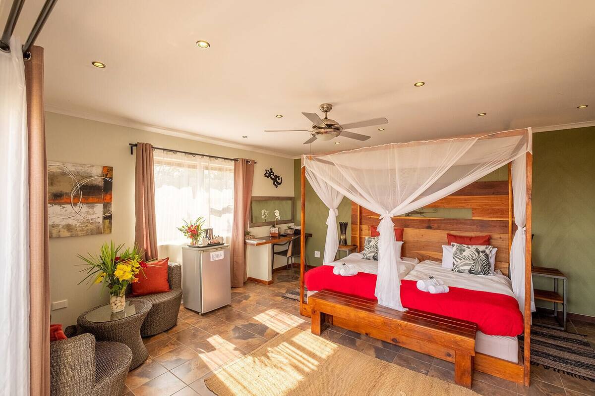 A bedroom with a four-poster bed, a desk, and a chair.