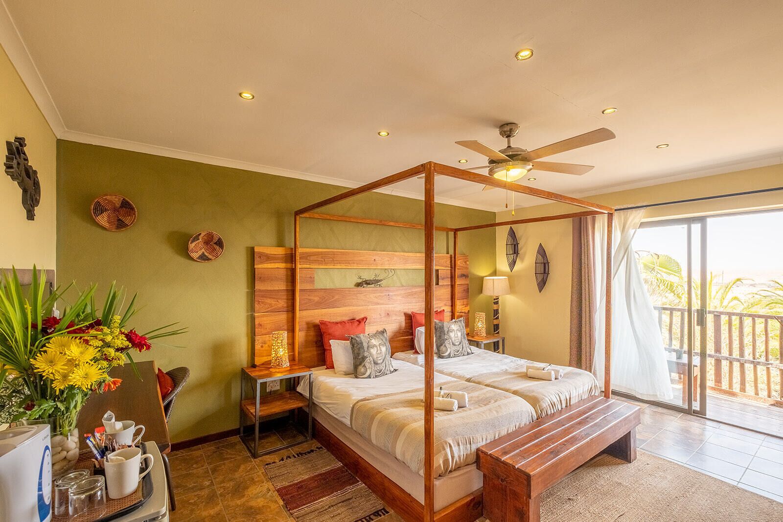 A four-poster bed with a wooden headboard, a ceiling fan, and a view of the outdoors through a sliding glass door.