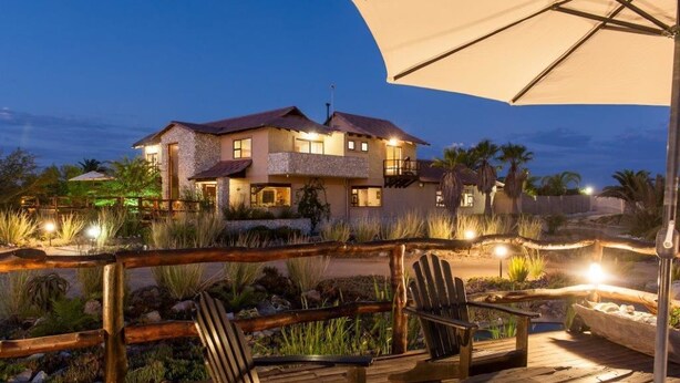 A large house with a balcony, surrounded by a wooden deck and outdoor seating. - Gecko Ridge Guest House (Swakopmund)