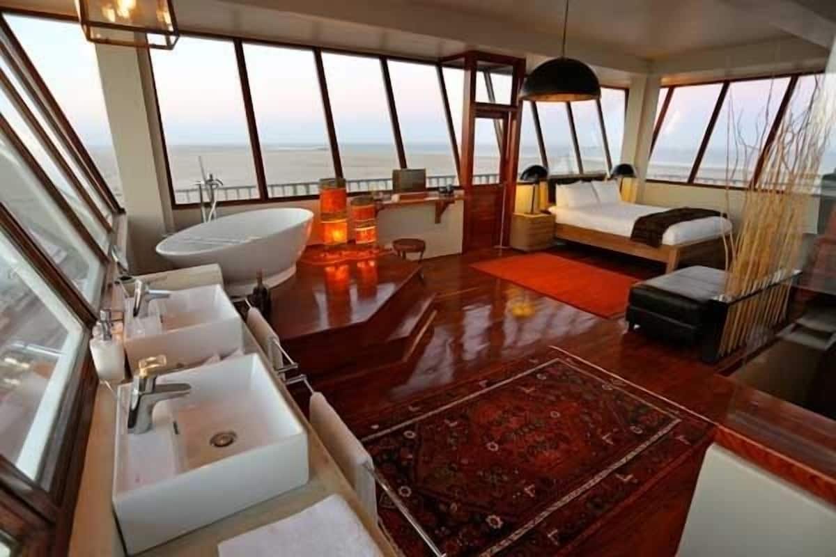 A luxurious cabin with a large window, a bathtub, a desk, and a bed.