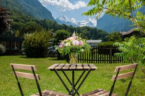 A wooden table with a vase of flowers in a garden with a mountain backdrop. - Jungfrau Hotel Annex Alpine Inn (Wilderswil)