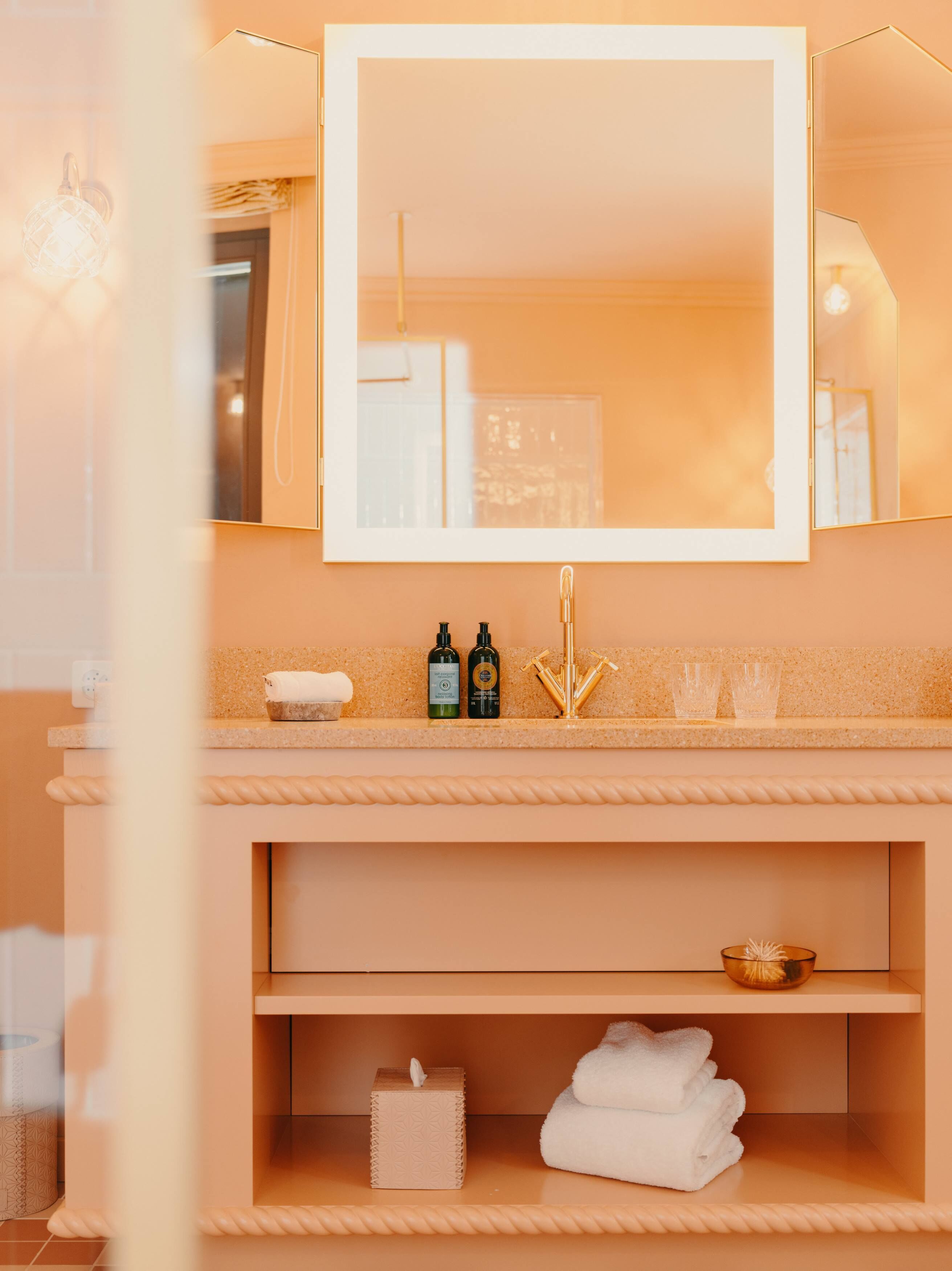 A bathroom with a beige countertop, a mirror, a sink, and a towel rack.