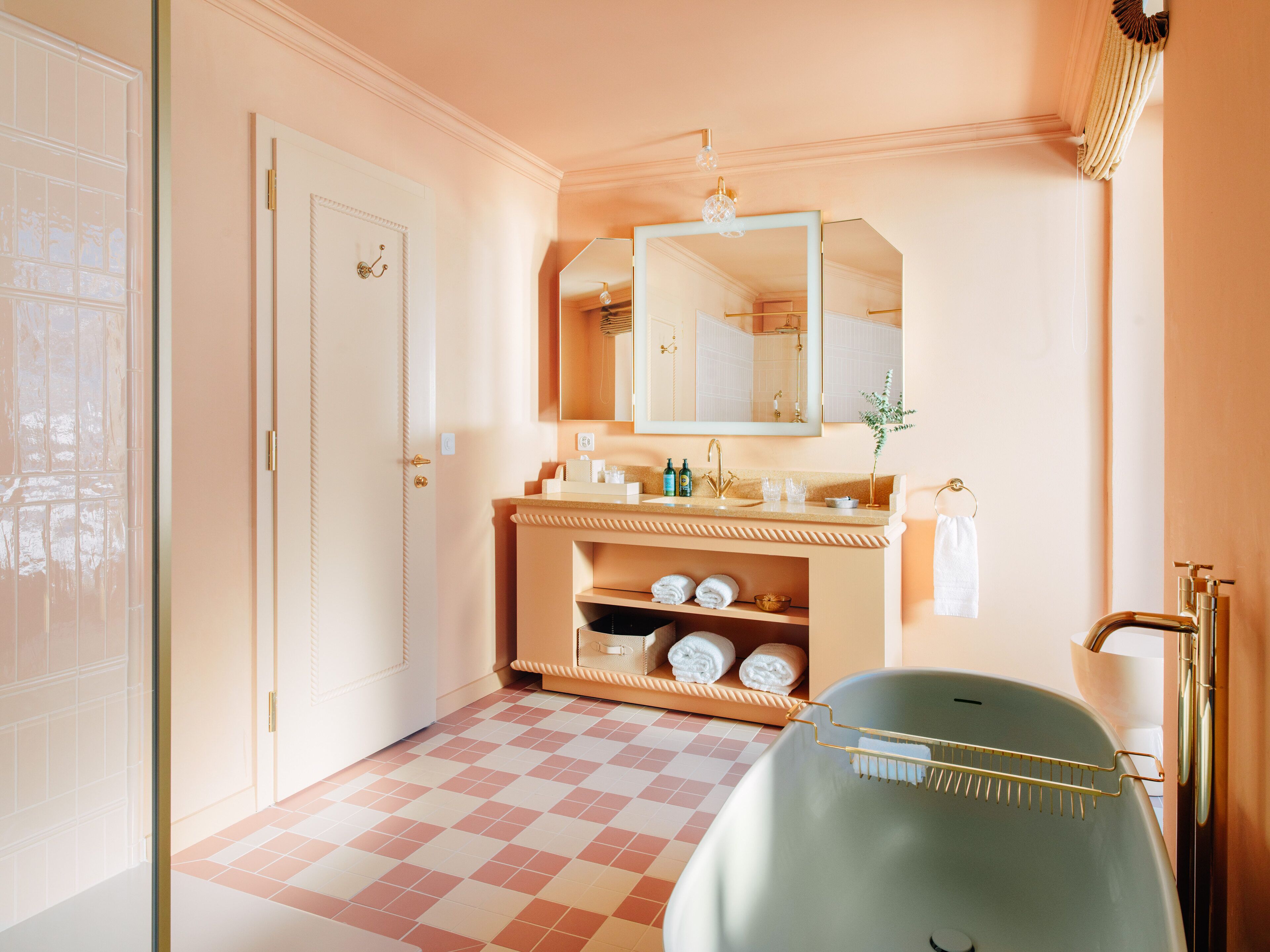 Une salle de bain avec un lavabo, un miroir, un porte-serviettes et un carrelage à motifs à carreaux.