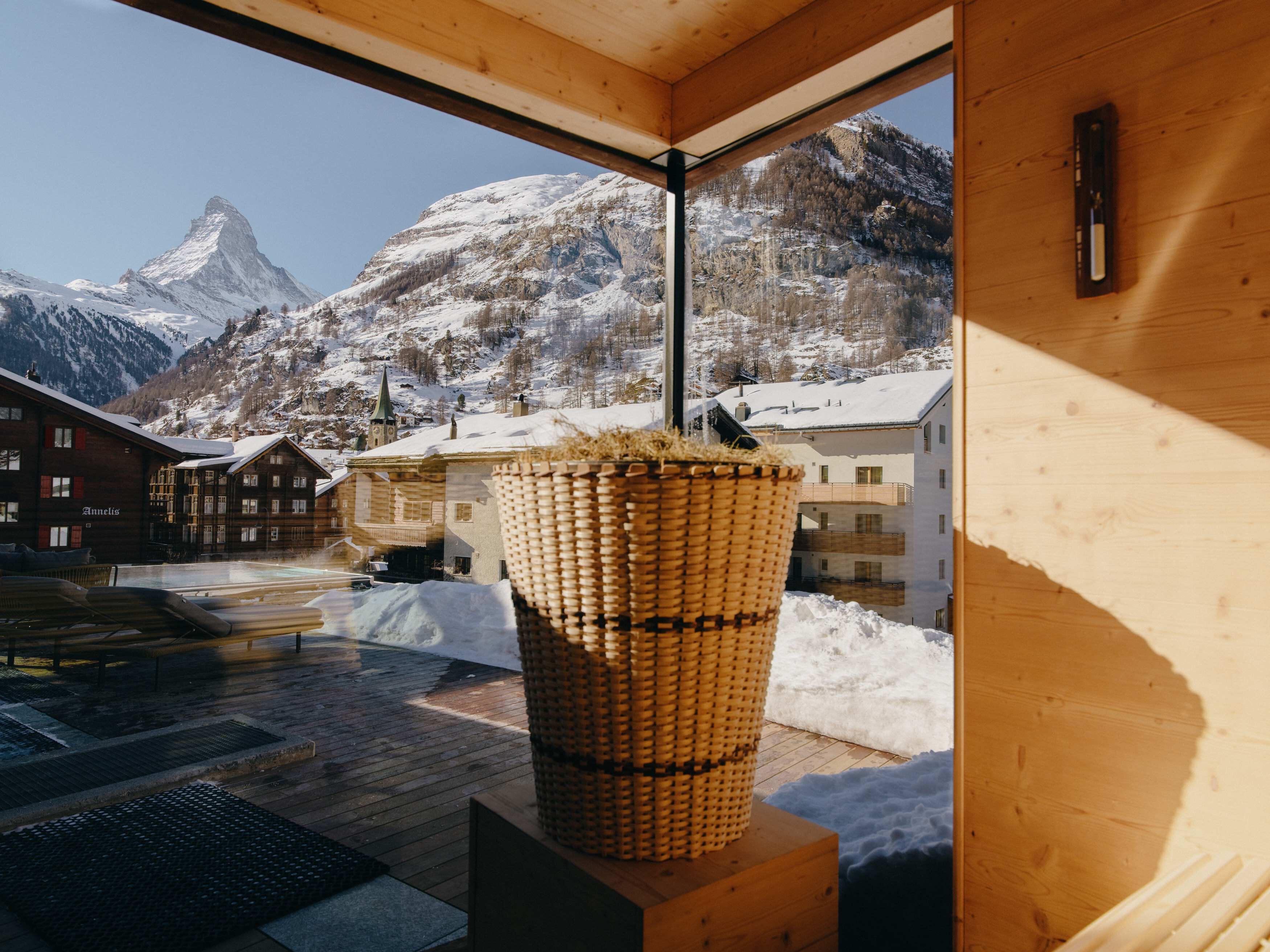 A wooden interior with a large window overlooking a snowy mountain landscape.