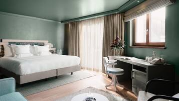 Une chambre d’hôtel comprenant un lit, un bureau, une chaise et une petite table agrémentée d’un objet décoratif.