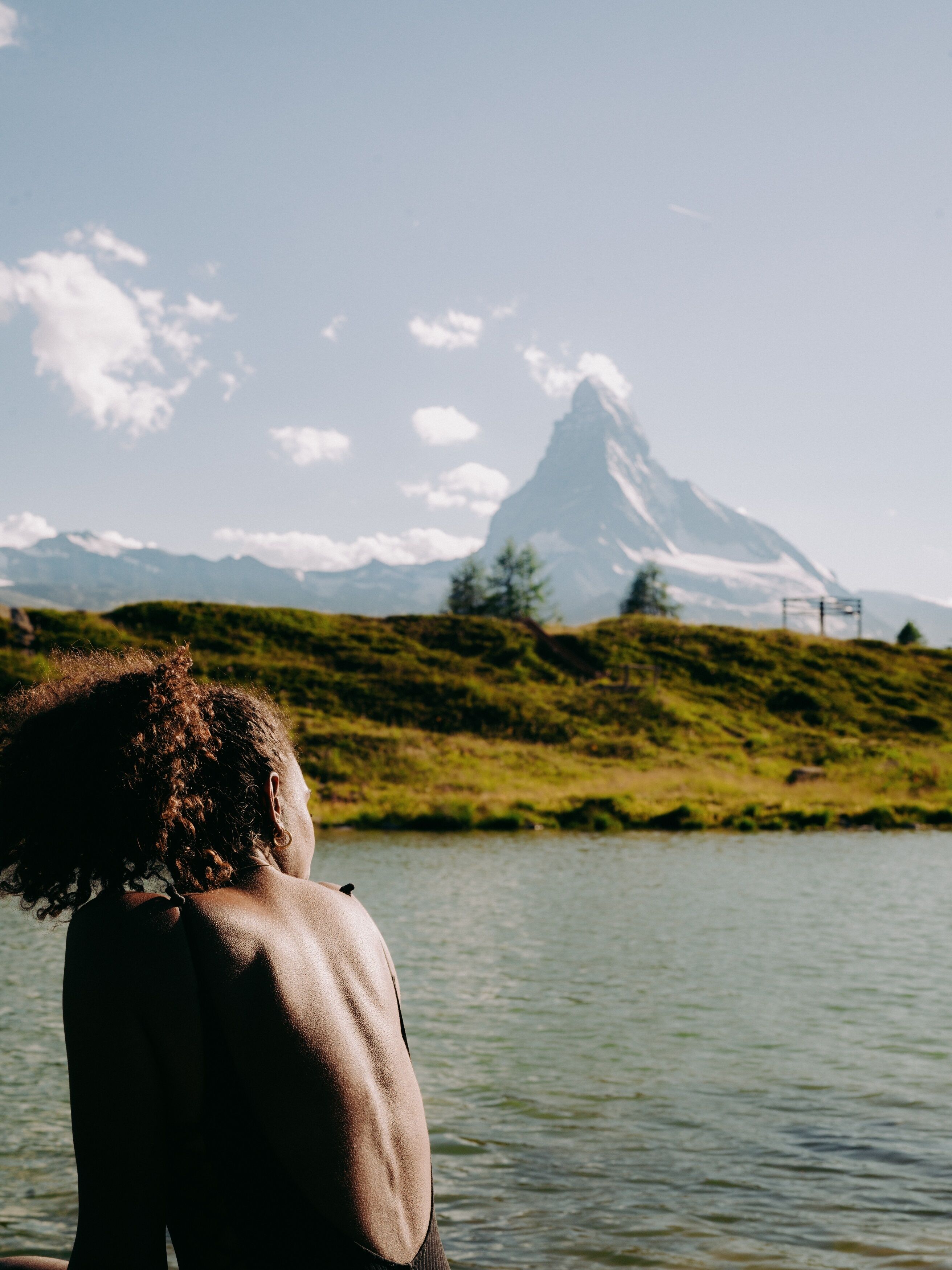 A person standing by a lake with a mountain in the background.