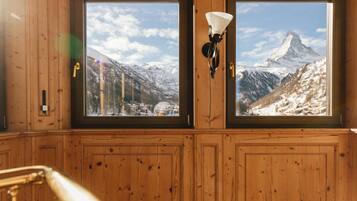 A wooden room with two large windows offering a view of a snowy mountain.