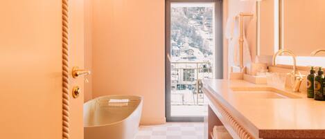 A modern bathroom with a freestanding bathtub, a large mirror, and a view of a snowy landscape through the window.