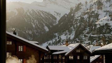 Un hotel con varias construcciones de madera, un patio cubierto de nieve y una montaña al fondo.