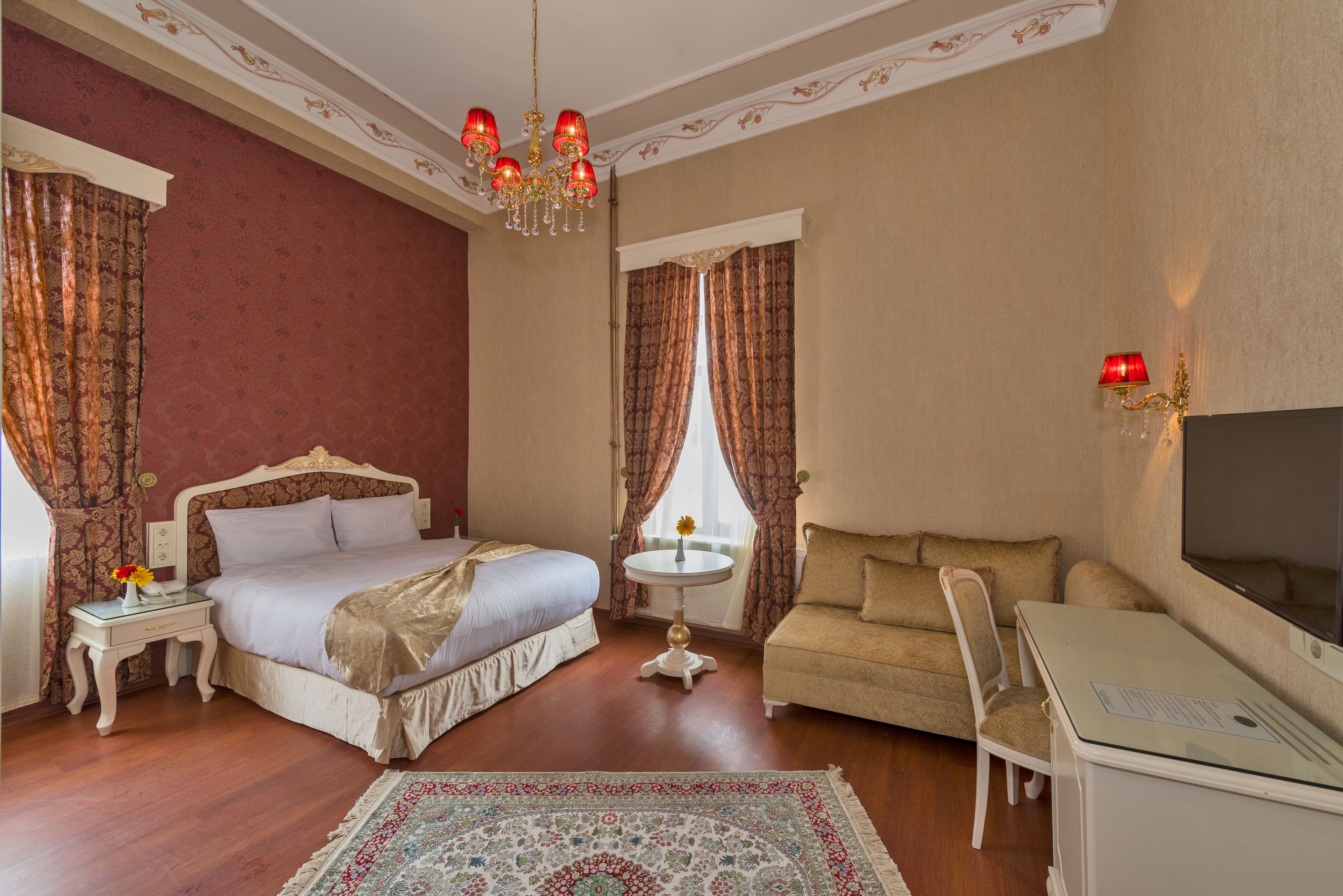 A hotel room with a large bed, a sofa, a desk, and a TV.