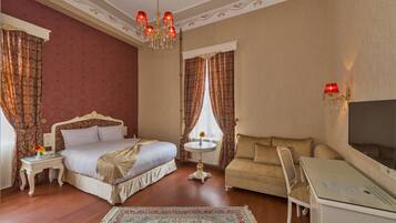 A hotel room with a large bed, a sofa, a desk, and a TV.