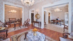 Un salón espacioso con una araña, muebles elegantes y un espejo grande.