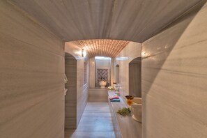 A narrow, tiled hallway with a wooden ceiling and a view into a room with a tiled wall and a white door. - Enderun Hotel (Istanbul)