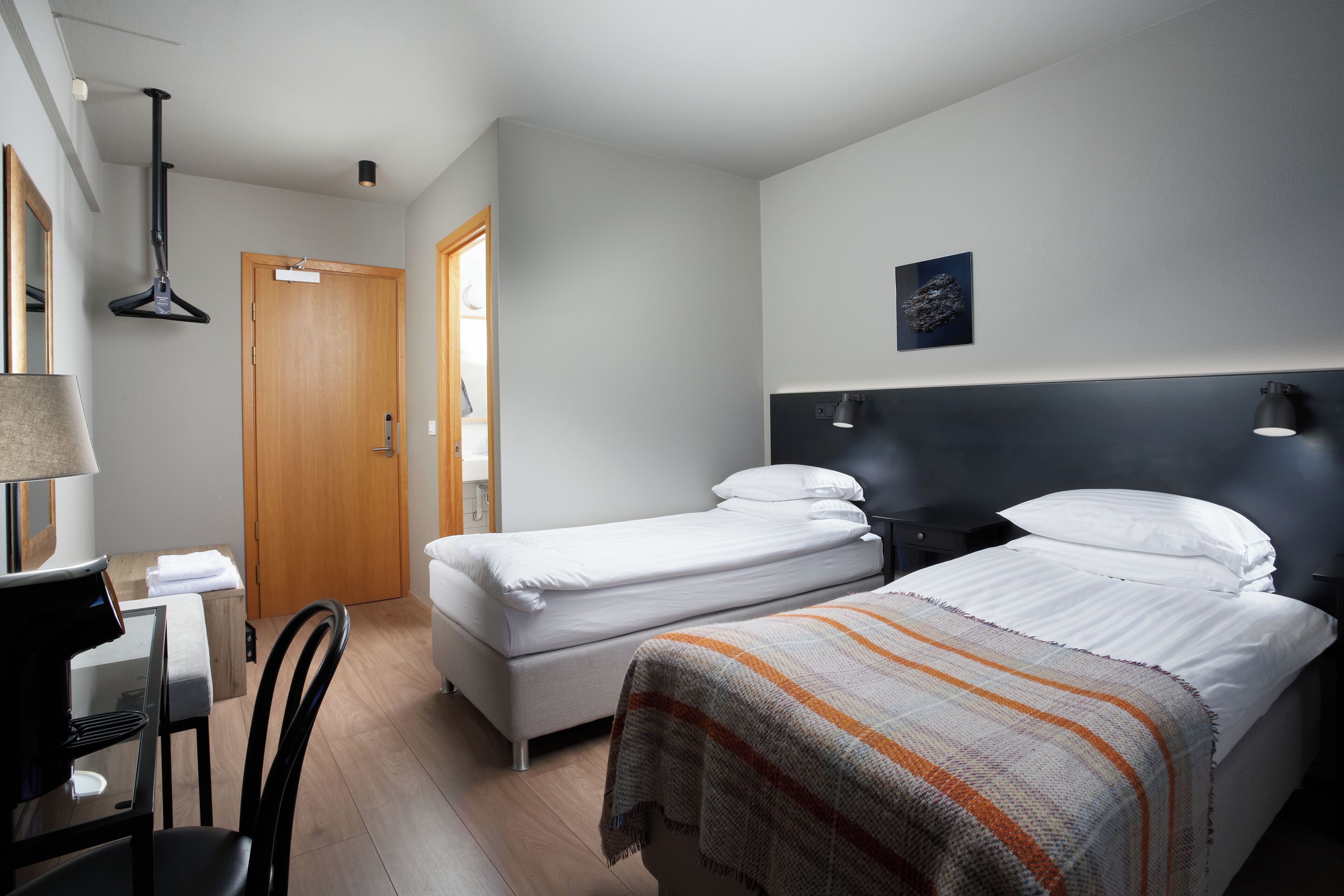 Una habitación de hotel con dos camas, un escritorio, una silla y una puerta.