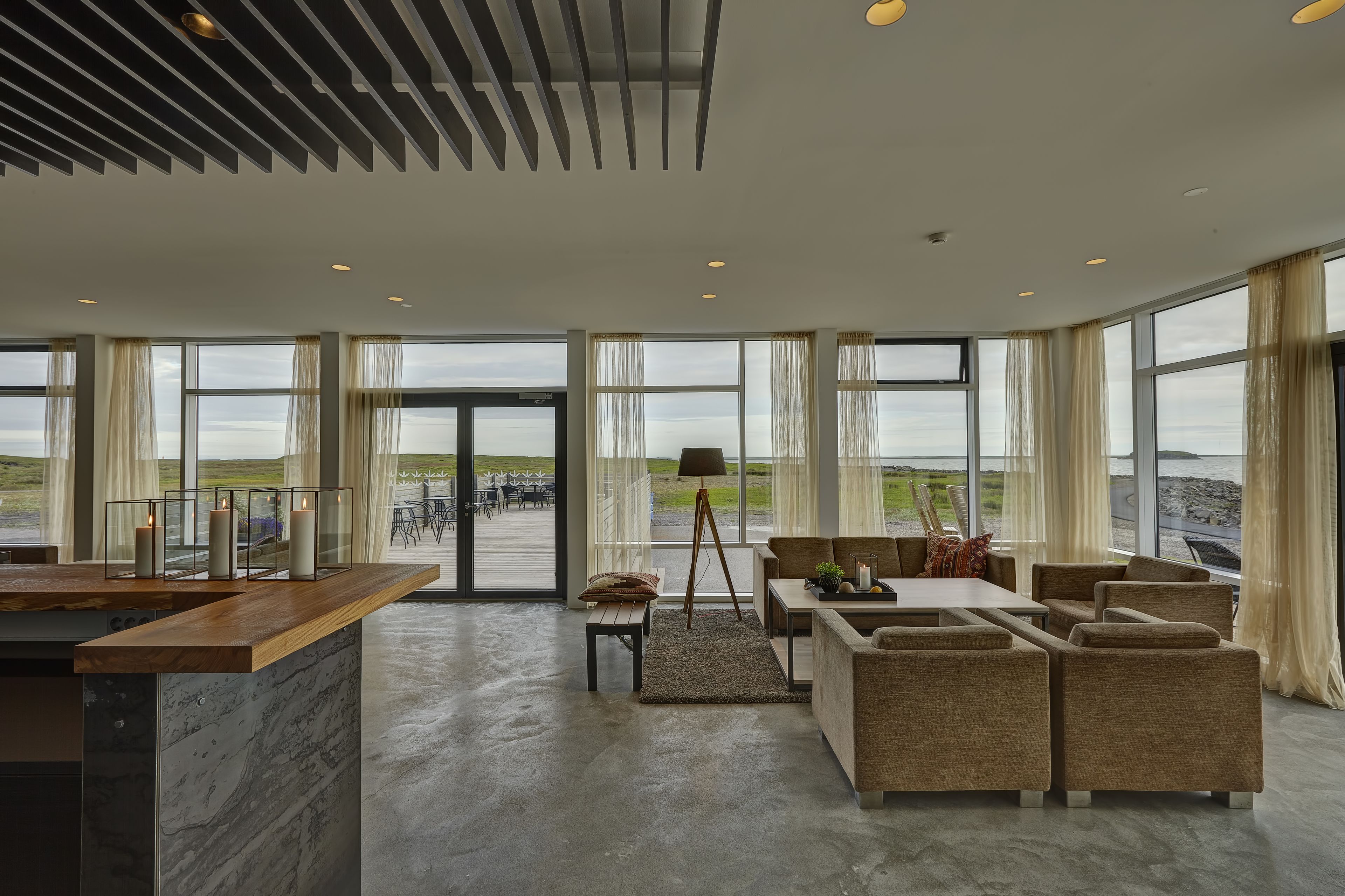 A spacious living area with a large window overlooking a scenic landscape, a wooden coffee table, and comfortable seating.