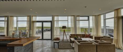 A spacious living area with a large window overlooking a scenic landscape, a wooden coffee table, and comfortable seating.