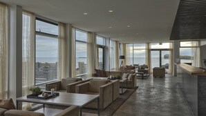 A spacious living area with large windows, a modern kitchen, and a view of the city. - Höfn - Berjaya Iceland Hotels (Höfn)