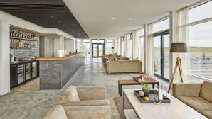 A spacious hotel lobby with a bar area, seating arrangements, and large windows offering views. - Höfn - Berjaya Iceland Hotels (Höfn)
