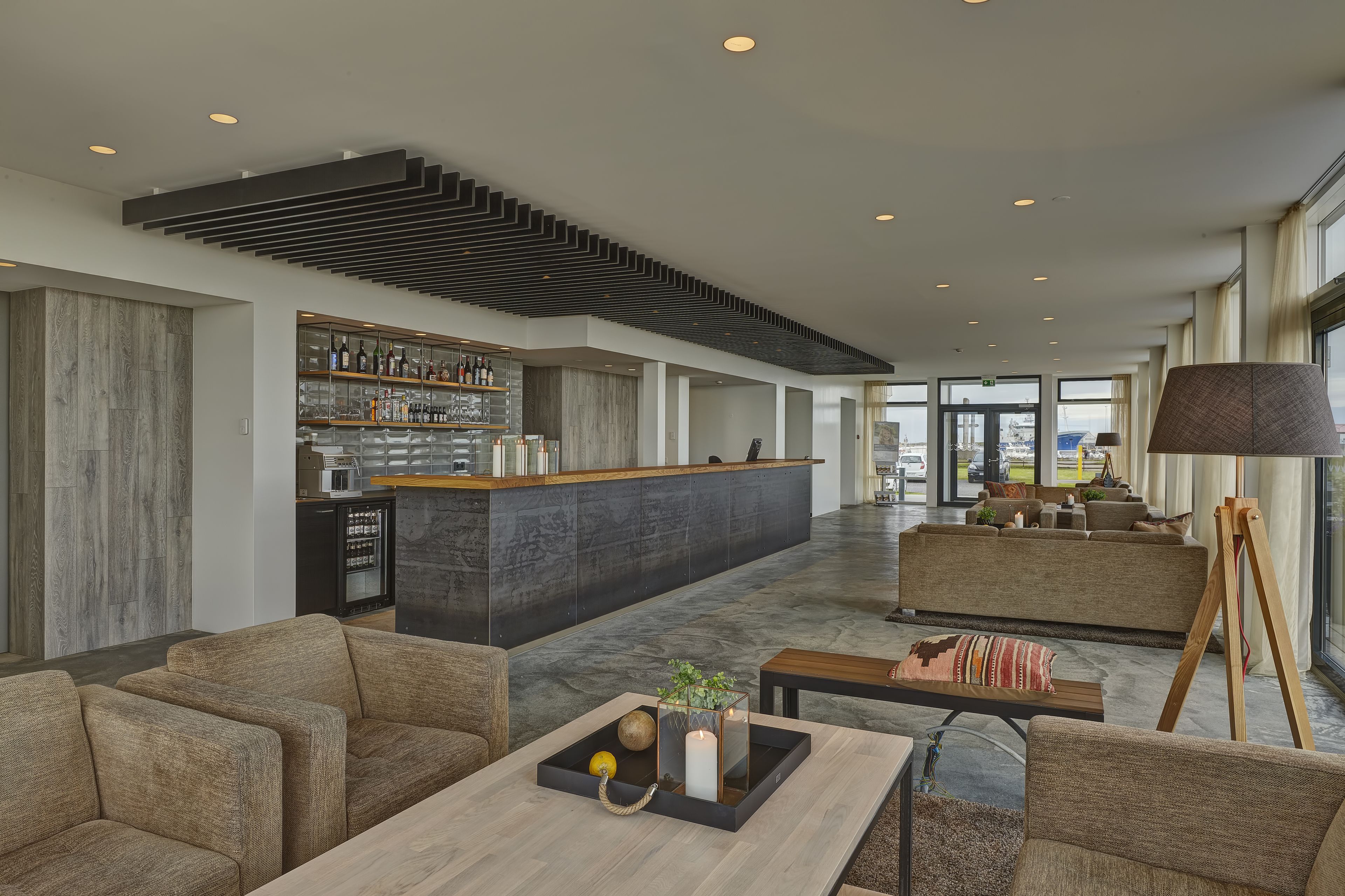 A spacious lobby with a modern bar area, comfortable seating, and a large window offering a view.