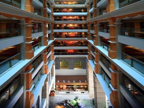 A multi-level hotel atrium with a central open space, multiple floors, and a variety of amenities. - Babylon Hotel (Dongguan)