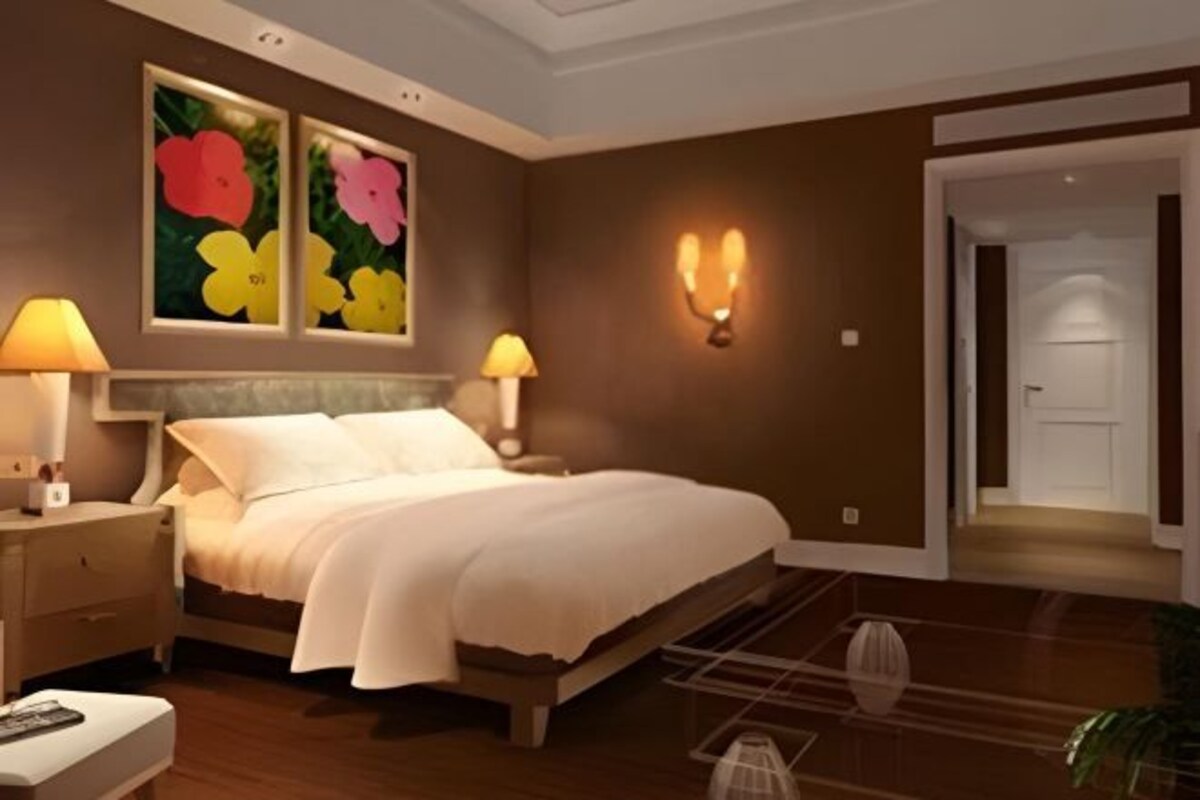 Ein Schlafzimmer mit Bett, Nachttischen, Wandleuchten und einer Tür zu einem anderen Raum.