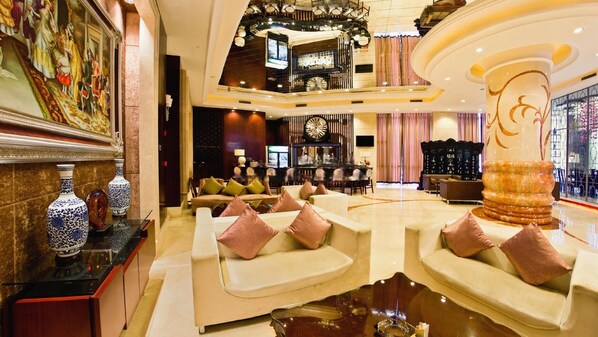 A spacious lobby with seating areas, a bar, and a large decorative fountain. - Babylon Hotel (Dongguan)
