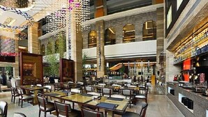 A spacious indoor dining area with multiple tables and chairs, a bar area, and a high ceiling with decorative lighting. - Babylon Hotel (Dongguan)