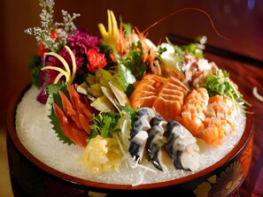A sushi platter with various types of fish and garnishes. - Babylon Hotel (Dongguan)