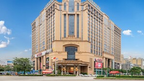 A large, multi-story hotel with a classic architectural design, featuring a central entrance and multiple balconies. - Babylon Hotel (Dongguan)