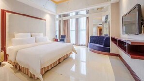 A modern hotel room with a large bed, a TV, and a seating area with a sofa and armchairs. - Babylon Hotel (Dongguan)