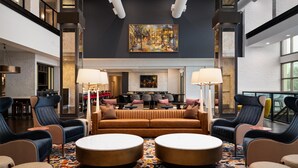 A spacious lobby with a central seating area, a fireplace, and a large painting on the wall. - Hilton Garden Inn Charleston Waterfront/Downtown (Charleston)
