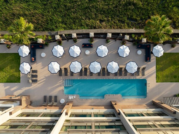 Una piscina al aire libre, sombrillas, sillones reclinables de piscina