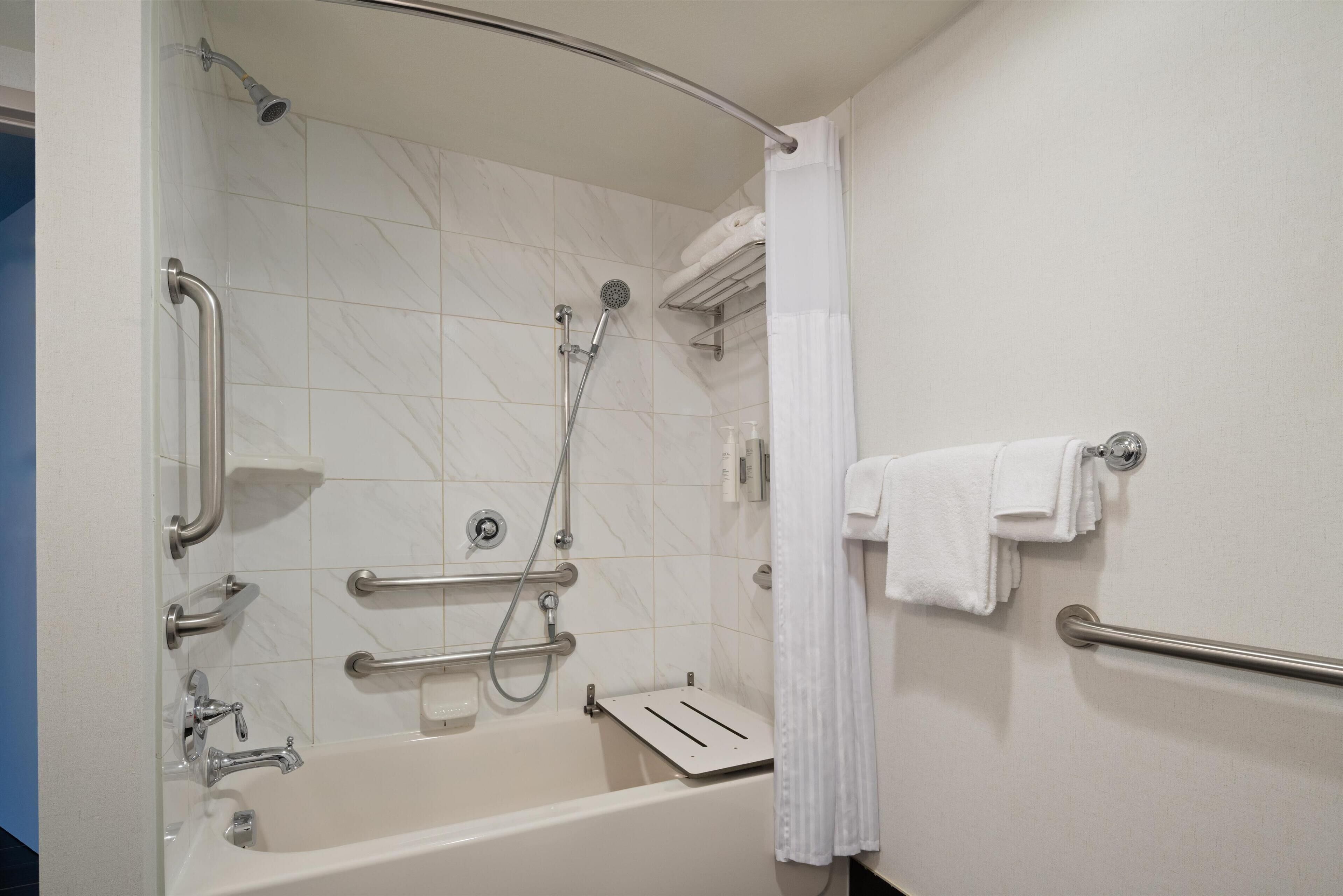 A modern bathroom with a walk-in shower, grab bars, and a towel rack.