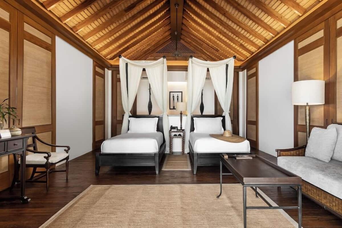 A room with two beds, a sofa, a desk, and a lamp.