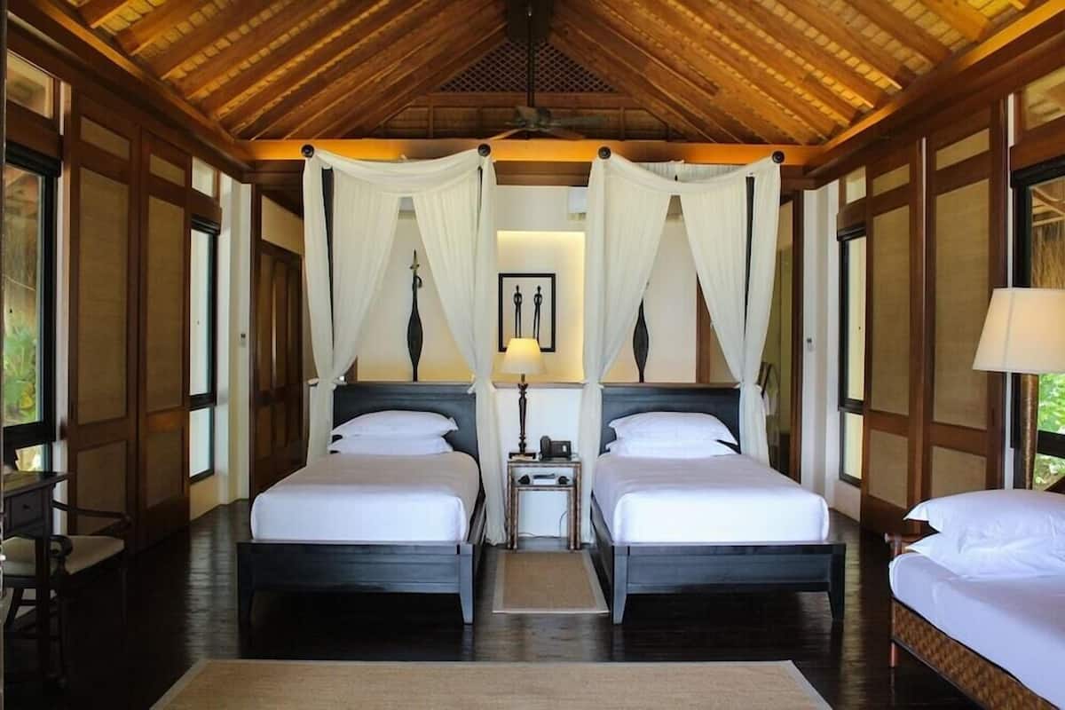 A room with two beds, a nightstand, a lamp, and a ceiling fan.