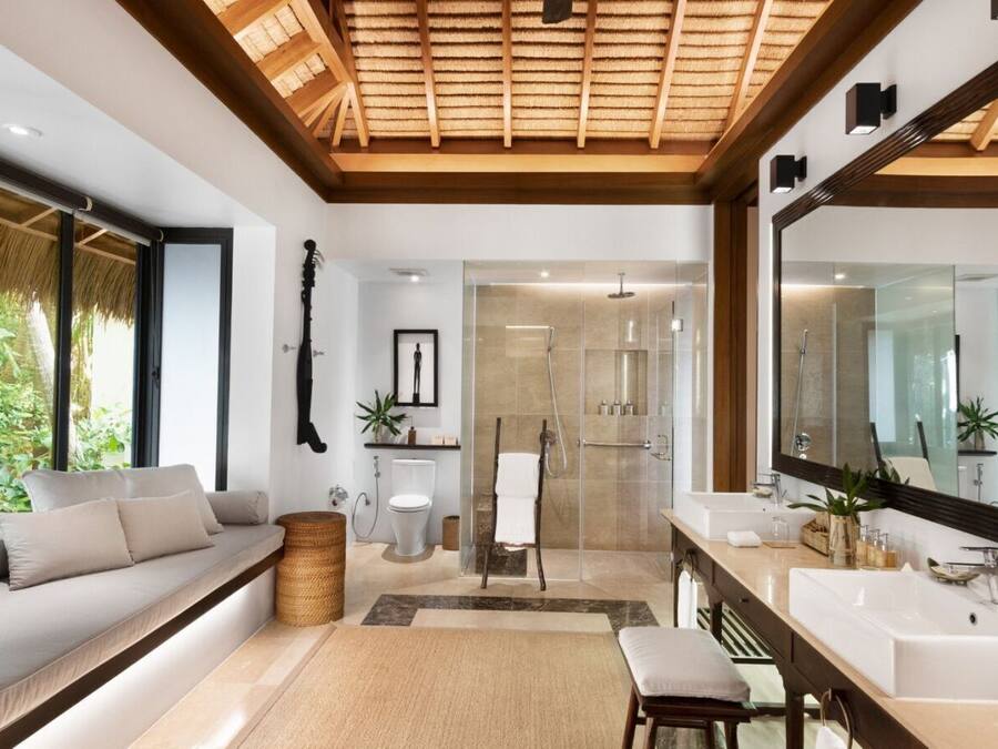 A modern bathroom with a large mirror, two sinks, and a shower area.