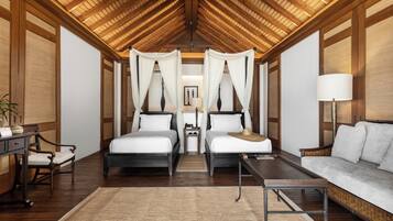 A room with two beds, a sofa, a table, and a ceiling fan.