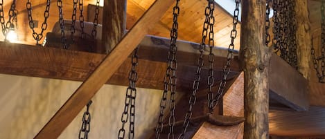 A wooden staircase with metal chains hanging from the ceiling, leading to an upper level.