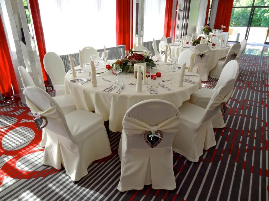Une table de salle à manger ronde, entourée de chaises blanches, chacune ornée d’un motif en forme de cœur sur le dossier.