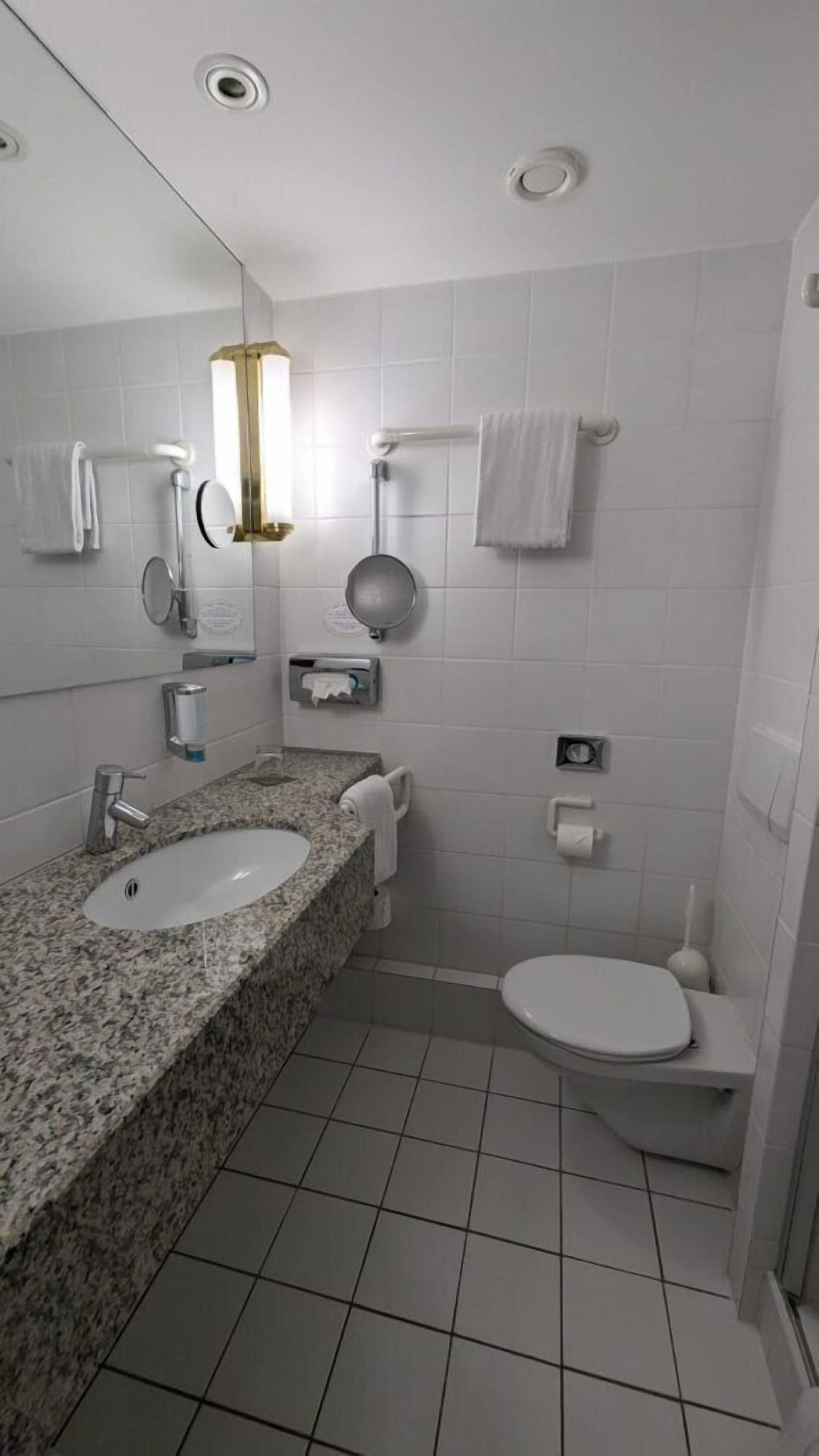 Ein modernes Badezimmer mit einem Granittisch, einem Spiegel, einer Toilette und einer Duschkabine.
