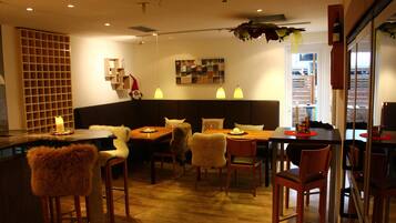 A modern dining area with wooden furniture, pendant lighting, and a central seating arrangement.