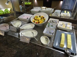 A buffet with various food items and condiments, including bowls of fruit, yogurt, and butter. - Hotel Scheidberg (Wallerfangen)