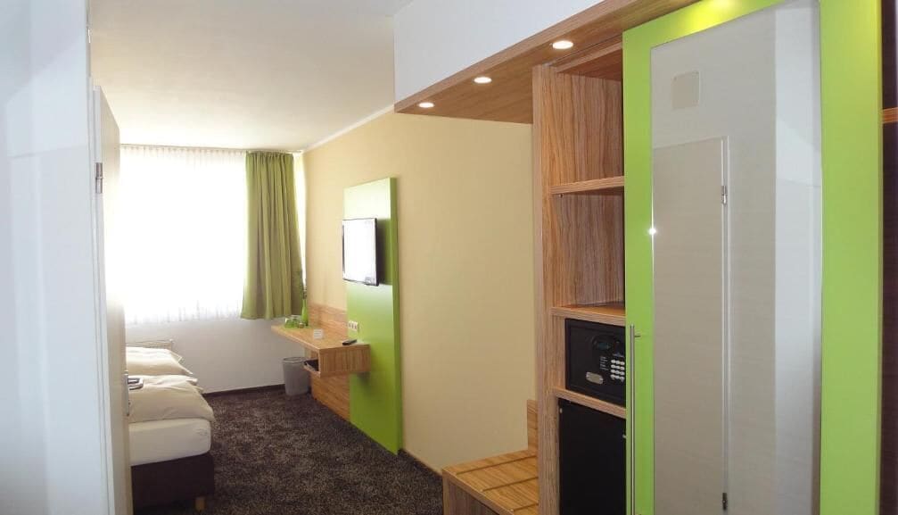 A hotel room with a bed, a desk, a television, and a wardrobe.