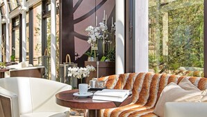 A modern interior with a sofa, a round table with a cup and saucer, and a vase with white flowers. - Romantik Hotel Schloss Rettershof (Kelkheim)
