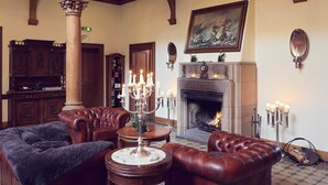 A traditional room with a fireplace, leather sofas, a wooden cabinet, and a large mirror on the wall. - Romantik Hotel Schloss Rettershof (Kelkheim)