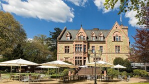 A large, historic building with a stone facade, multiple windows, and a prominent entrance. - Romantik Hotel Schloss Rettershof (Kelkheim)